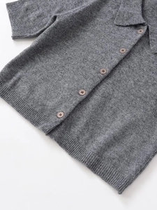 Dettaglio del cardigan in maglia grigia a maniche corte con bottoni classici