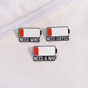 Detailed view of NEED series battery enamel pins on a white canvas bag surface