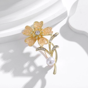 Close-up of golden flower brooch with sparkling rhinestones and a large cream pearl