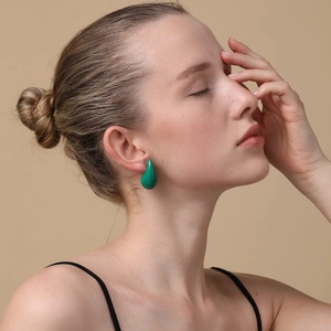 Close-up of emerald green teardrop earrings in smooth finish worn by a model