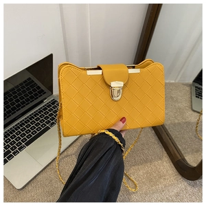Detail of yellow woven faux leather shoulder bag with golden metallic clasp and chain