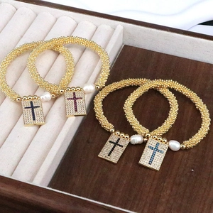 Classic gold cross bracelets with heart charms and colorful zircons in a wood jewelry box