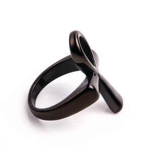 Macro shot of polished black stainless steel cross cut-out ring with mirror finish on white background