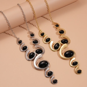 Close-up of gold and silver chunky necklaces with irregular black oval resin pendants