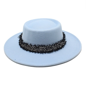 Detalle de un sombrero boater de lana azul claro con banda de tweed en blanco y negro