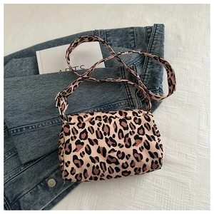 Detailed close-up of a leopard print crossbody bag styled on a blue denim jacket background