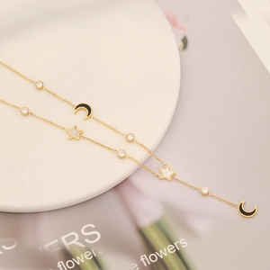 Elegant gold double layer necklace with black moon and white star charms on a white plate