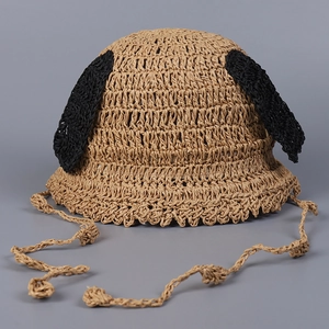 Detail of handmade straw sun hat featuring cute black dog ears and braided chin strap