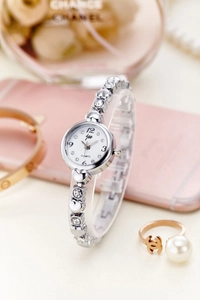 Detail of silver heart bracelet watch with white dial and crystal accents on a jewelry set