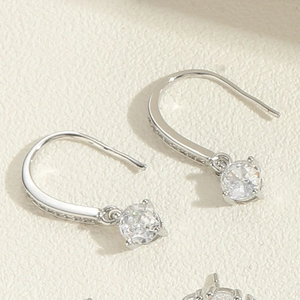 Macro detail of silver dangle earrings with round clear zircon and small crystal accents