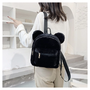 Detail of cute black plush backpack with bear ears shown on model in a modern room