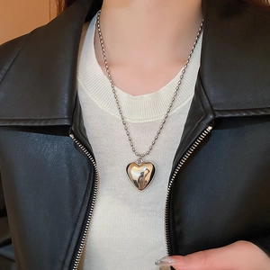 Close-up of polished silver heart pendant necklace on a ball chain worn by a model