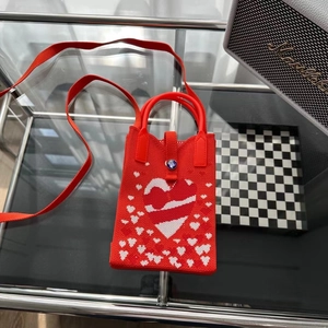Texture tricotée détaillée du mini sac bandoulière rouge avec motifs de cœur et boucle bijou