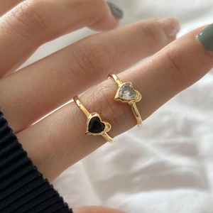 Close-up of gold rings with black and clear heart-shaped zircons worn on hand