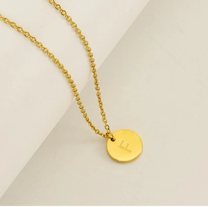 Vue macro d'un collier doré en acier inoxydable avec pendentif rond gravé de la lettre F