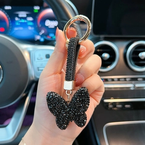 Close-up of black rhinestone butterfly keychain with gold ring in a car setting