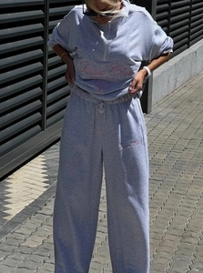 Detail of grey half-zip sweatshirt and drawstring sweatpants with pink Tennis Club embroidery