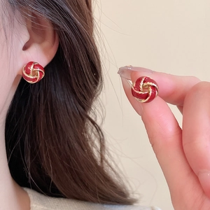 Macro detail of red enamel and gold-plated knot earrings with a model wearing view