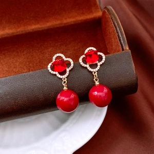 Macro view of vintage style red clover earrings with zircon inlay and hanging pearl charm