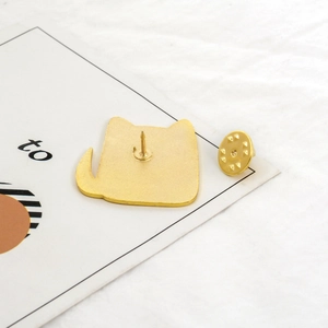 Detailed close-up of golden cat enamel pin with metal butterfly clutch backing and card
