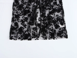 Detail view of sheer black lace blouse hem with floral flocking and delicate ties