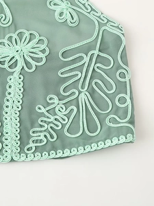Vue détaillée de la broderie florale vert clair sur le tissu vert de l'ensemble