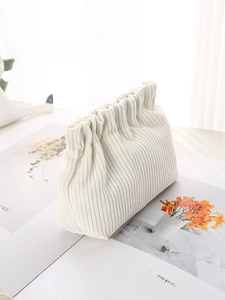 Detail of white corduroy mini pouch with cloud-like gathered elastic closure and soft texture