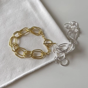 Detail of heavy double-layered link bracelets in gold and silver finish with OT buckle