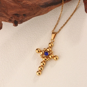 Detailed close-up of a vintage gold cross necklace featuring a central blue zircon stone