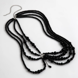 Detail of multi-layer black bead necklace with silver chain and teardrop pendant