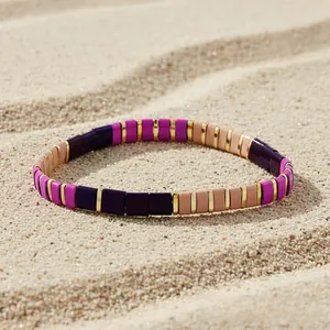 Detailed macro view of colorful Tila bead stretch bracelet on natural sand background