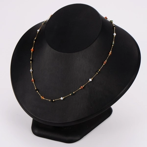 Gold stainless steel necklace featuring colorful natural stone beads on a display stand