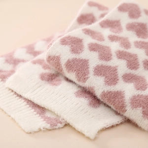 Detailansicht aus weichem cremefarbenem Strick mit rosa Herzen und Rippbündchen für Babys