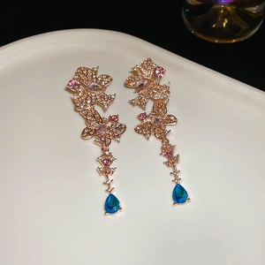 Detailed macro view of rose gold long tassel earrings with blue waterdrop zircon pendants