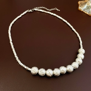 Detailed shot of silver heart fringe necklace with meteorite texture beads and lobster clasp