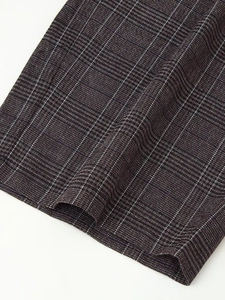 Gros plan sur le motif à carreaux foncés et les coutures de l'ourlet du pantalon