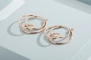 Detailed top view of rose gold triple-layered twisted hoop earrings on blue background