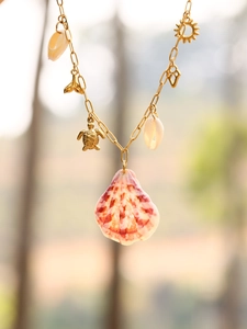 Detail of bohemian gold chain necklace with natural shell, sea turtle and mermaid tail charms