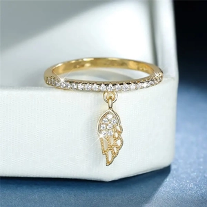 Macro view of a gold-plated feather charm ring with cubic zirconia on a jewelry box