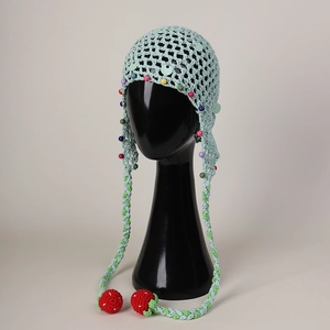 Detail of mint green crochet hat with colorful beads, sequins and strawberry pendants