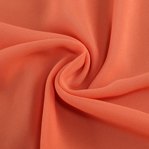 Vista macro del tessuto in chiffon corallo con delicate balze e un morbido drappeggio