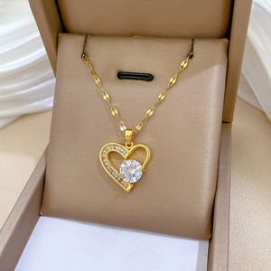Macro shot of heart pendant with baguette zircons and large center stone on gold chain
