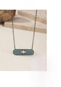 Detailed view of a black punk necklace featuring a blue pavé rectangle pendant with a star