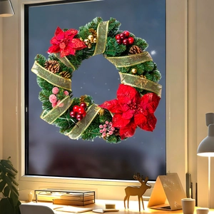 Close-up of a Christmas wreath with pine cones and red poinsettia on a window