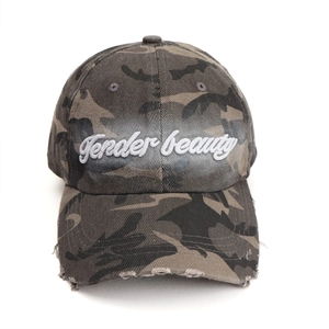 Detailed view of camouflage baseball cap with white Tender beauty embroidery and frayed brim
