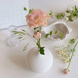 Nahaufnahme der modernen weißen Keramikvase mit horizontaler Rillenstruktur und Blumen