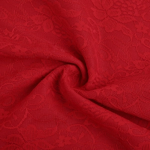 Macro detail of red lace fabric with intricate floral patterns and cutout textures