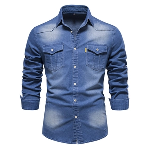 Detail of mid-blue washed denim shirt featuring double chest pockets and fabric texture