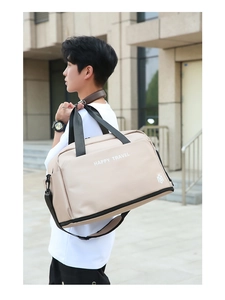 Outdoor shot of a beige travel bag with black straps and Happy Travel print