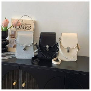 Three elegant crossbody mini bags in silver, black and beige on a minimalist shelf